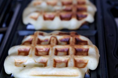 Elektrikli waffle ızgarasında Belçika waffle 'ı. Wafer pişirme, sağlıklı kahvaltı hazırlama.