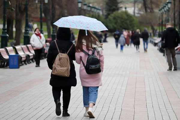 雨の都市では 1つの傘を持つ2人の女の子の人々の背景に通りを歩く 雨の日 春の嵐 — ストック写真