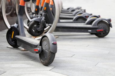 Otoparkta arka arkaya elektrikli scooterlar. Şehir bisiklet kiralama sistemi, sokakta elektronik scooterlar.