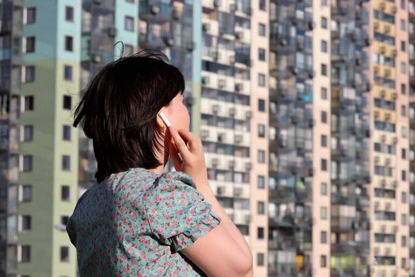 Mujer Toca Auriculares Inalámbricos Oído Pie Los Edificios Residenciales Fondo — Foto de Stock