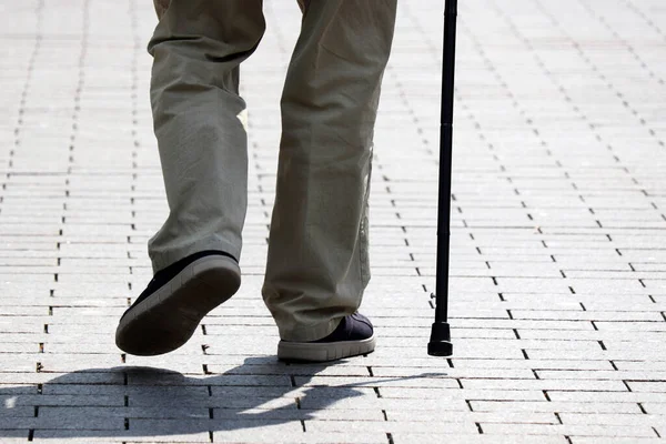 Man walking with a cane down the street. Concept of old age, diseases of the spine or joint disease, elderly people