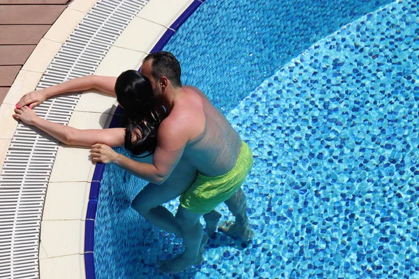 Passionate couple hugs and kisses in the pool, top view. Romantic vacation or honeymoon, passion and love