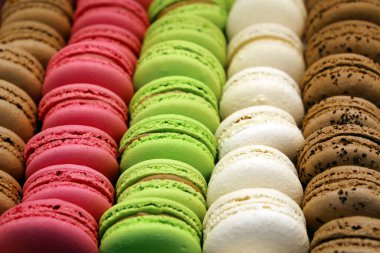 Makarnalar arka arkaya. Renkli, tatlı bir arka plan. Çilekli, vanilyalı ve çikolatalı bademli kurabiyeler.