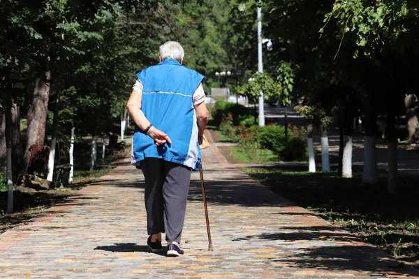 町の公園の通りに杖で歩く老婦人 人を限定し 背骨の病気 高齢者 — ストック写真