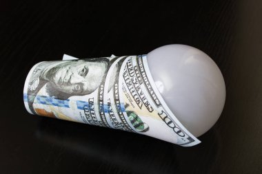 Tahta bir masaya dolarla sarılı ampul.