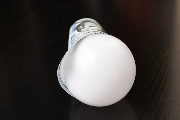 Light Bulb Wrapped Dollars Wooden Table — Stock Photo, Image