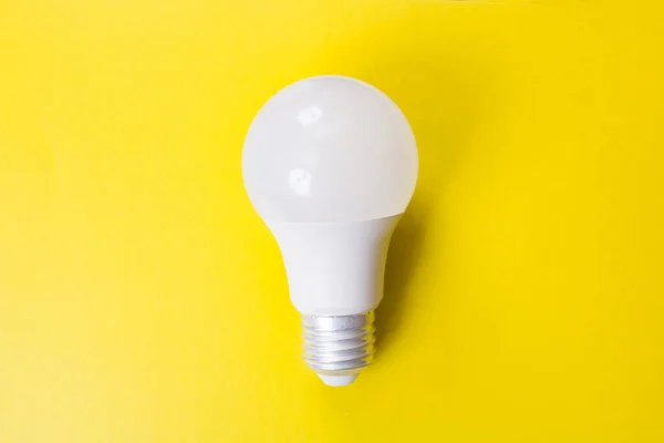 Light bulb on bright yellow background closeup — Stock Photo, Image