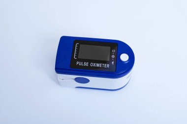 Mavi arkaplanda bir nabız oksimetresi.