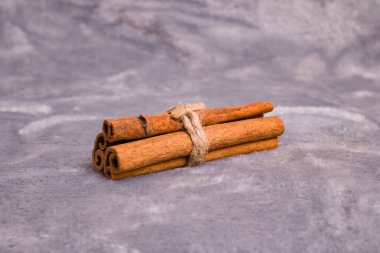 Gri arka planda üç tarçın çubuğu. Yakın plan.