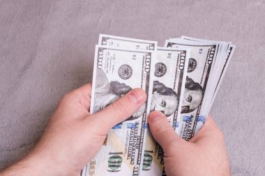 Eller gri bir arka planda dolar sayıyor.