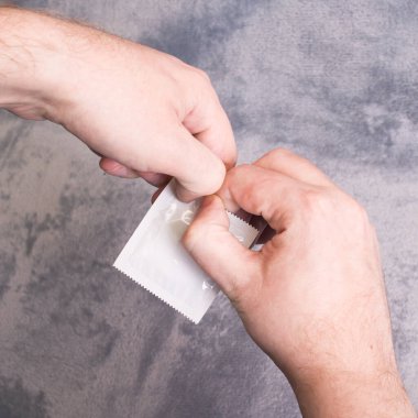 Gri arka planda prezervatif var. Yakın plan.