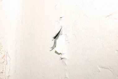 Beyaz bir duvarın boyası soyuluyor.