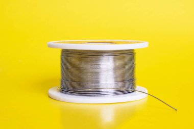 Sarı arka planda metal tel makarası yakın plan