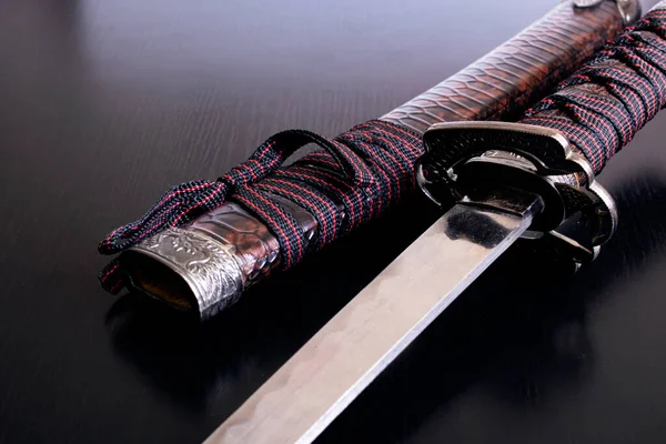 Samurai sword and scabbard on wooden background close up