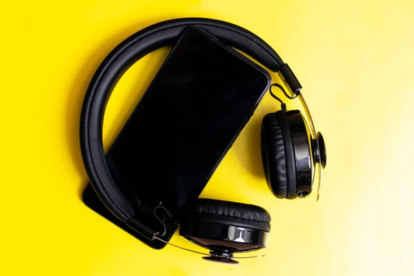 Headphones and phone on a yellow background close up