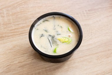 Tahta bir masada siyah bir kasede peynir çorbası. Yaklaş.