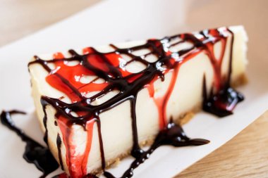 Tahta masaya ahududu ve çikolata soslu cheesecake.