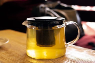 Ahşap bir masada çay ile şeffaf bir çaydanlık yakın çekim