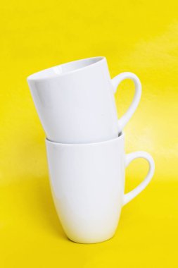 Sarı arka planda iki beyaz kupa. Yakın plan.