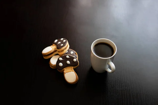 Mushroom shaped cookies and cup of coffee on a wooden table close up