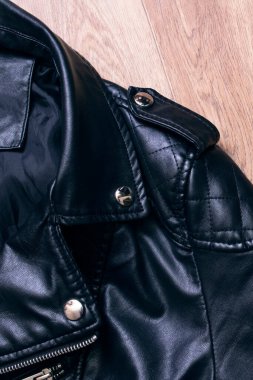 Ahşap arka planda siyah deri ceket. Yakın plan.