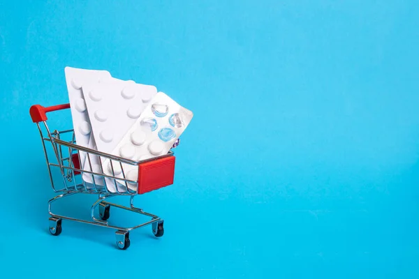 青い背景の買い物かごの中の丸薬 コピースペース — ストック写真
