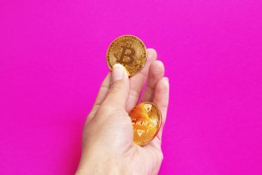 Pembe arka planda Bitcoinsa elinde. Yakın plan.