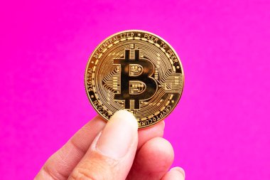 Pembe arka planda Bitcoinsa elinde. Yakın plan.