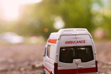 Güneş ışığında ağaçların arasında asfalt üzerinde ambulans arabası