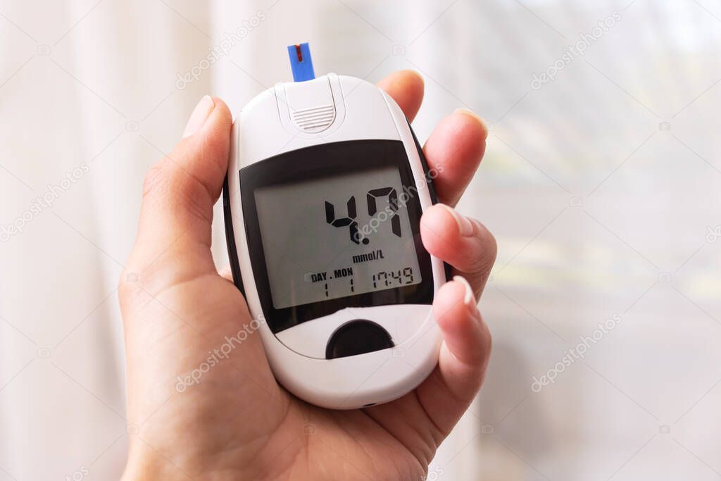 Blood glucose meter in hand on white background close up