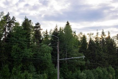 Mavi bulutlu gökyüzüne karşı feneri ve elektrik kabloları olan bir sütun.