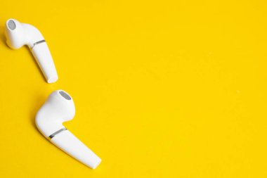 Sarı arkaplandaki kablosuz kulaklıklar, boşluğu kopyala