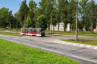 BELARUS, NOVOPOLOTSK - 18 AĞUSTOS, 2021: Yolun ortasındaki raylarda kırmızı tramvay sürüyor