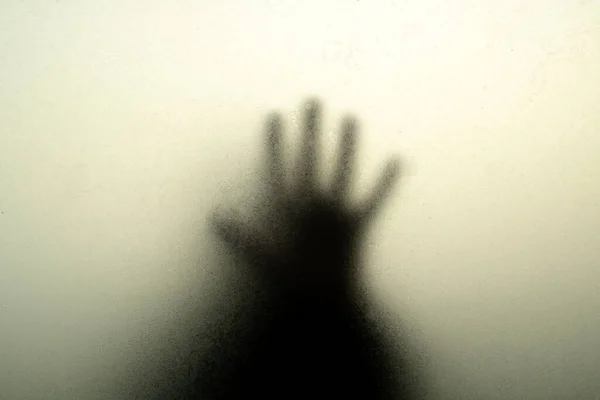 Mão silhueta preta atrás de vidro enevoado nas sombras — Fotografia de Stock