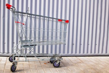 Bir alışveriş arabası metal bir duvara yakın duruyor.