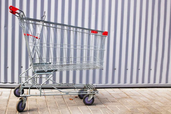 Een Winkelwagentje Staat Tegen Een Metalen Muur Van Dichtbij — Stockfoto