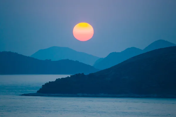 günbatımı üzerinde deniz ve dağlar