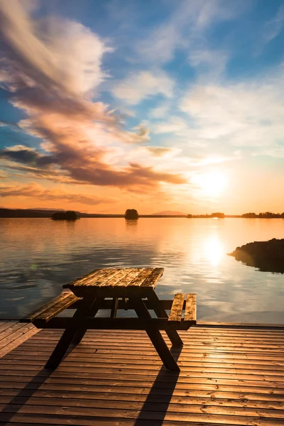 Bank op een houten pier bij zonsondergang — Stockfoto