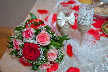 Kırmızı ve beyaz çiçekli altın alyanslar. Düğün buketindeki yüzükler. Nişan yüzükleri kurdele ile bağlanmış Seçici odak ve bulanık arkaplan