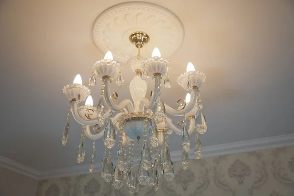 Luxurious interior chandelier with candles. A noble candelabrum with many small pearls hangs on the ceiling. A premium decoration for a palace gala, a business meeting in a villa or a wedding