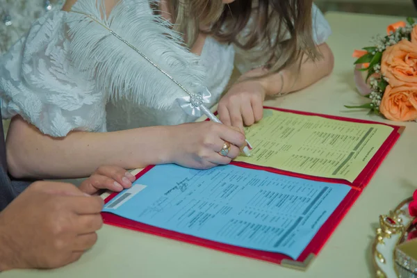 Novio y novia registran el matrimonio. La mujer pone su firma en la boda. Una mujer firma y registra su matrimonio con la mujer que ama: firma el contrato . — Foto de Stock