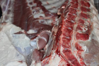 Taze domuz eti bir kasapta sergileniyor. Et net çizgiler ve dokular gösteriyor. Bu da kesin bir kesim olduğunu gösteriyor. Satılık et hazırlığının bir parçası..