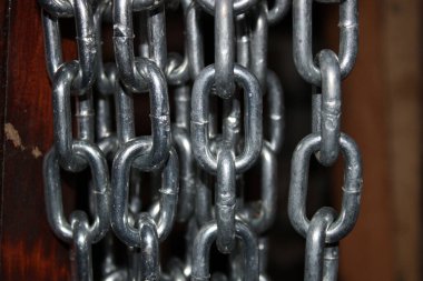 Metal halkalardan oluşan bir kolleksiyon bir zincir oluşturur. Zincir ahşap bir arka planda asılı. Halkalar parlak ve gümüş renginde..