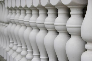 Sahnede arka arkaya dizilmiş bir dizi beyaz balya balığı sergileniyor. Her baluster yuvarlak bir şekle sahiptir, bir korkuluk ya da yapı boyunca sürekli bir çizgi oluşturur..