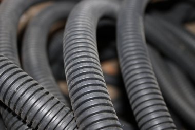 Birkaç siyah kauçuk hortum çalışma alanında birbirine dolanmış olarak görülüyor. Yüzey görülebilir ve hortumlar çeşitli doku ve desenleri gösterir. Sahneye ışık düşüyor..