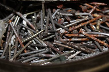 Büyük bir çivi çeşidi alet kutusunda yatıyor. Çiviler farklı boyut ve koşulları gösteriyor, bazıları paslı ve diğerleri parlak. Bu sahne inşaatçılar için ortak bir çalışma ortamı yakalar.