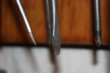 Ahşap bir yüzeyde çeşitli metal aletler sergilenir. Her aracın farklı bir şekil ve boyutu vardır, bu da bir atölye ortamında çeşitli görevler için kullanıldığını düşündürür.