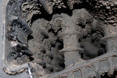 Toz ve kirle kaplı mekanik dişlilerin yakın görüntüsü. Sahne, çeşitli kısımlarda toprak birikintisi olan bir makinenin iç çalışmalarını gösteriyor..