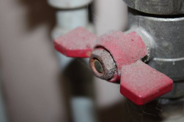 Kırmızı saplı bir vana tozla kaplıdır. Bakım alanında yer almaktadır. Ayarlar ihmal ve kullanım eksikliği belirtileri gösteriyor. Toz yüzeyde görülebilir..