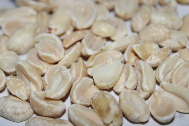 Düz bir yüzeye kurumuş beyaz fıstık koleksiyonu yayılır. Doğal ışık her bir yerfıstığının dokusunu ve şeklini vurgular ve soluk rengini gösterir..